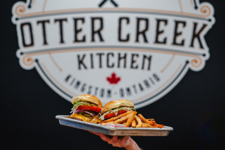 Burgers in front of the Otter Creek Kitchen sign