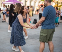 Two people holding hands, laughing, and dancing salsa at Market Square.